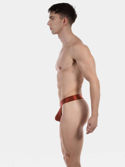 A man in profile wearing a satin red men's thong, photographed against a solid light gray background.