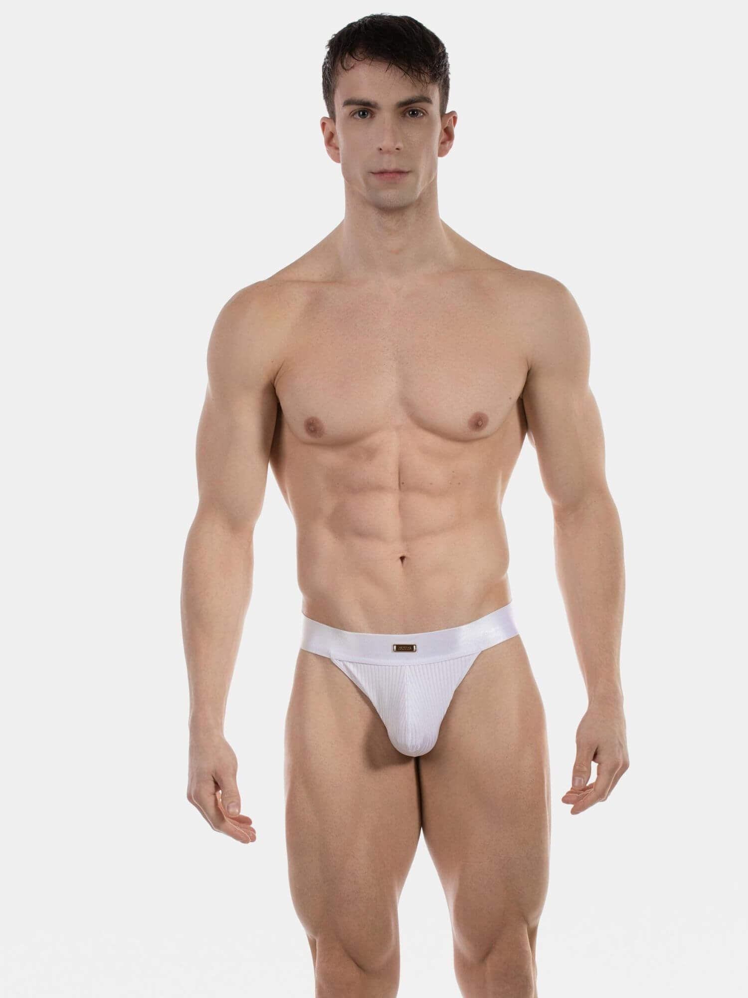 A muscular male model wearing a white low-rise brief, standing against a solid light gray background.