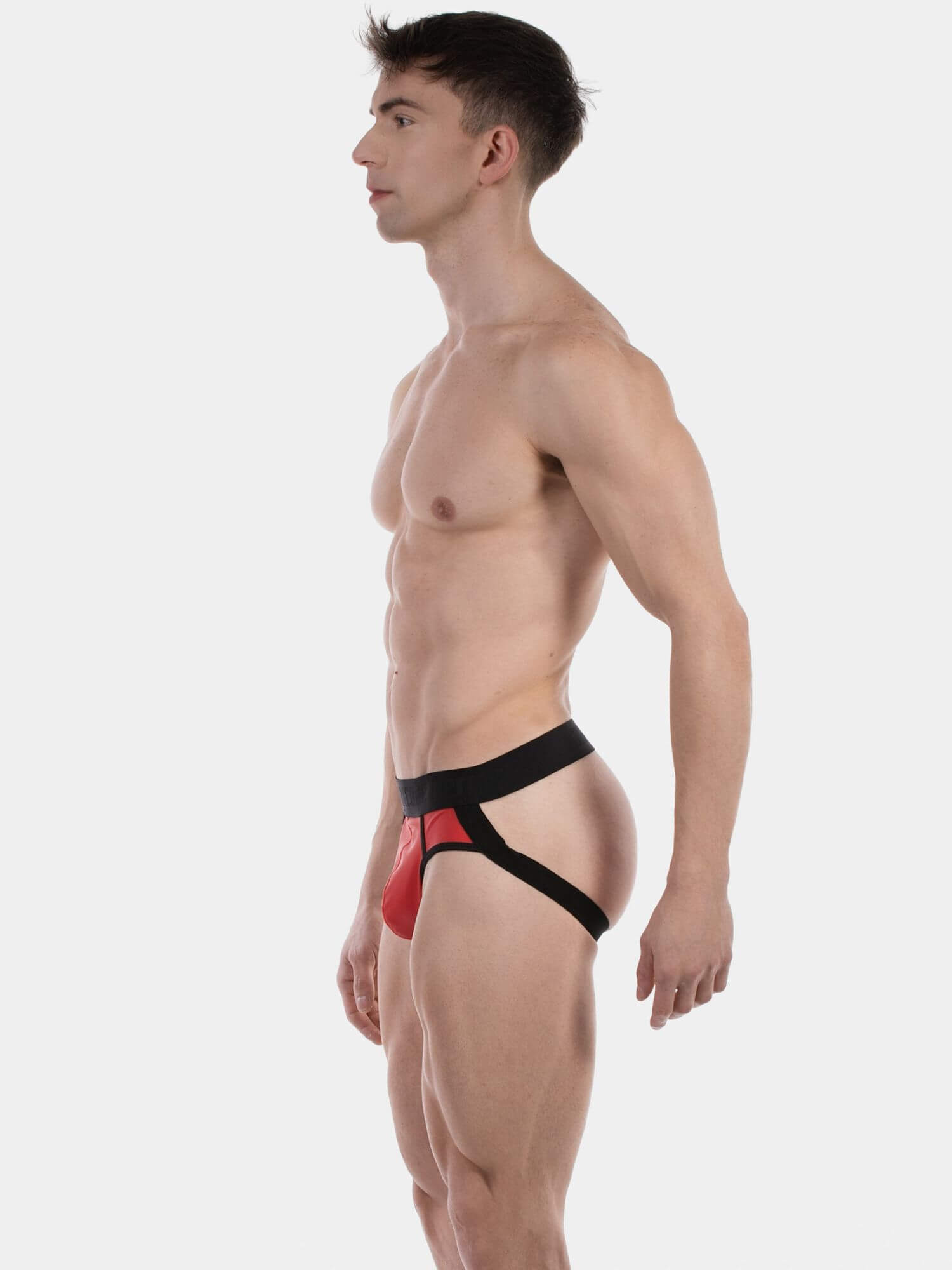 Man wearing a red and black jockstrap against a white background