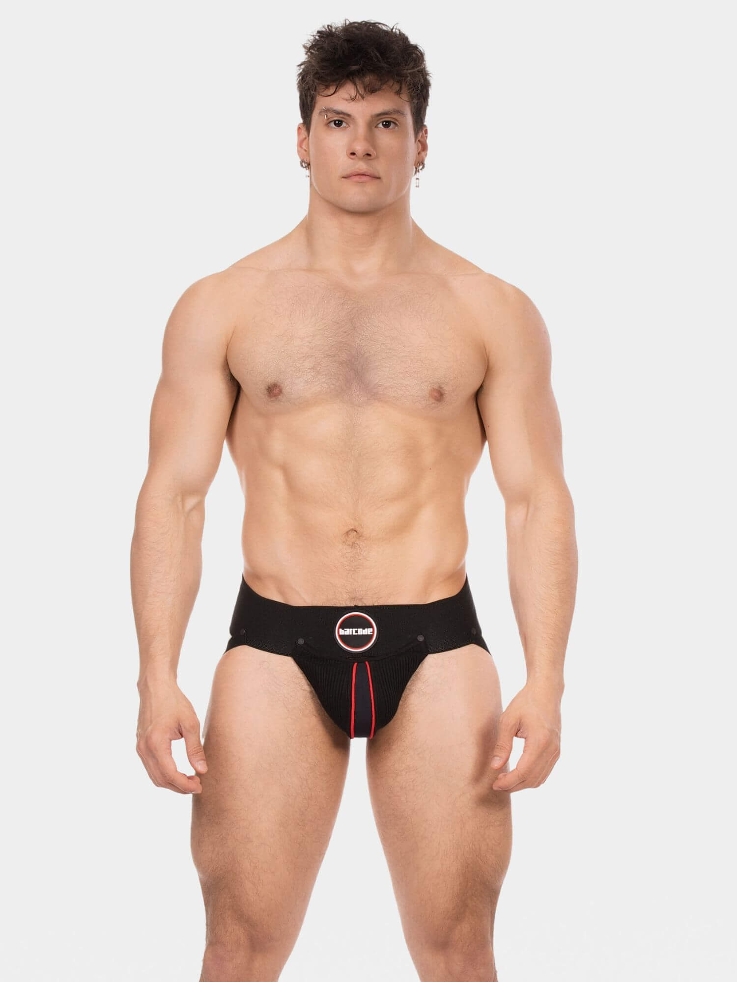 A muscular male model wearing black men's jock with a red drawstring and a circular logo patch on the front, set against a solid light gray background.