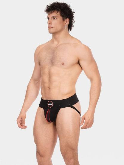 A shirtless male model wearing black men's jockstrap briefs with a red accent line and a circular logo emblem on the front, photographed against a light gray studio background.