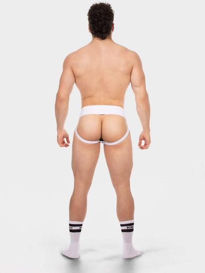 Rear view of a muscular man wearing white men's jock and white crew socks with black stripes, standing against a light gray studio background.