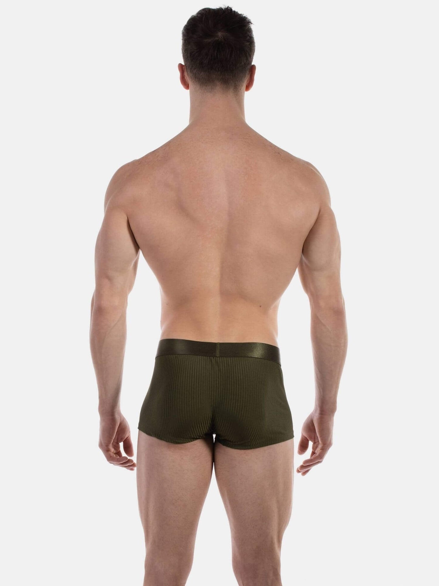 Rear view of a muscular man wearing olive green textured boxer briefs against a light gray studio background.