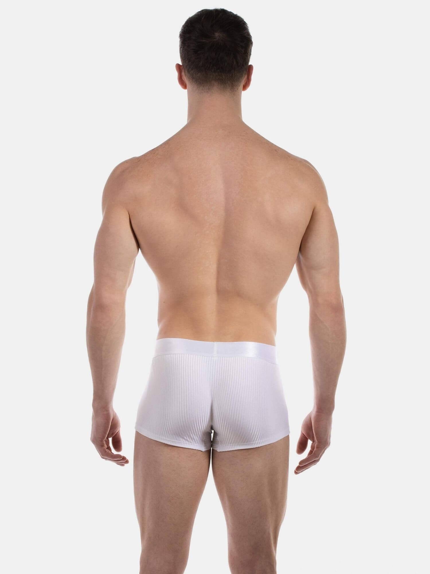 A man viewed from the back wearing white ribbed boxer briefs against a light gray studio background.