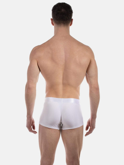 A man viewed from the back wearing white ribbed boxer briefs against a light gray studio background.