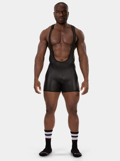 A muscular male model wearing a black wrestling singlet paired with black and white socks against a solid light gray background.