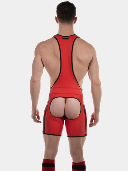 A muscular male model wearing a bright red wrestling singlet with black trim, paired with red and black socks, against a solid light gray background.