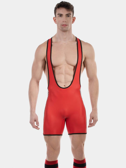A muscular male model wearing a bright red wrestling singlet with black trim, paired with red and black socks, against a solid light gray background.