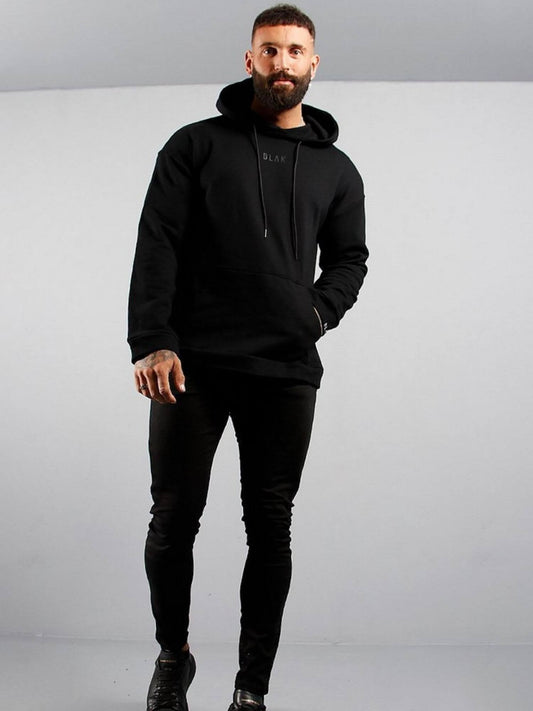 Man wearing a black hoodie and pants on a gray background