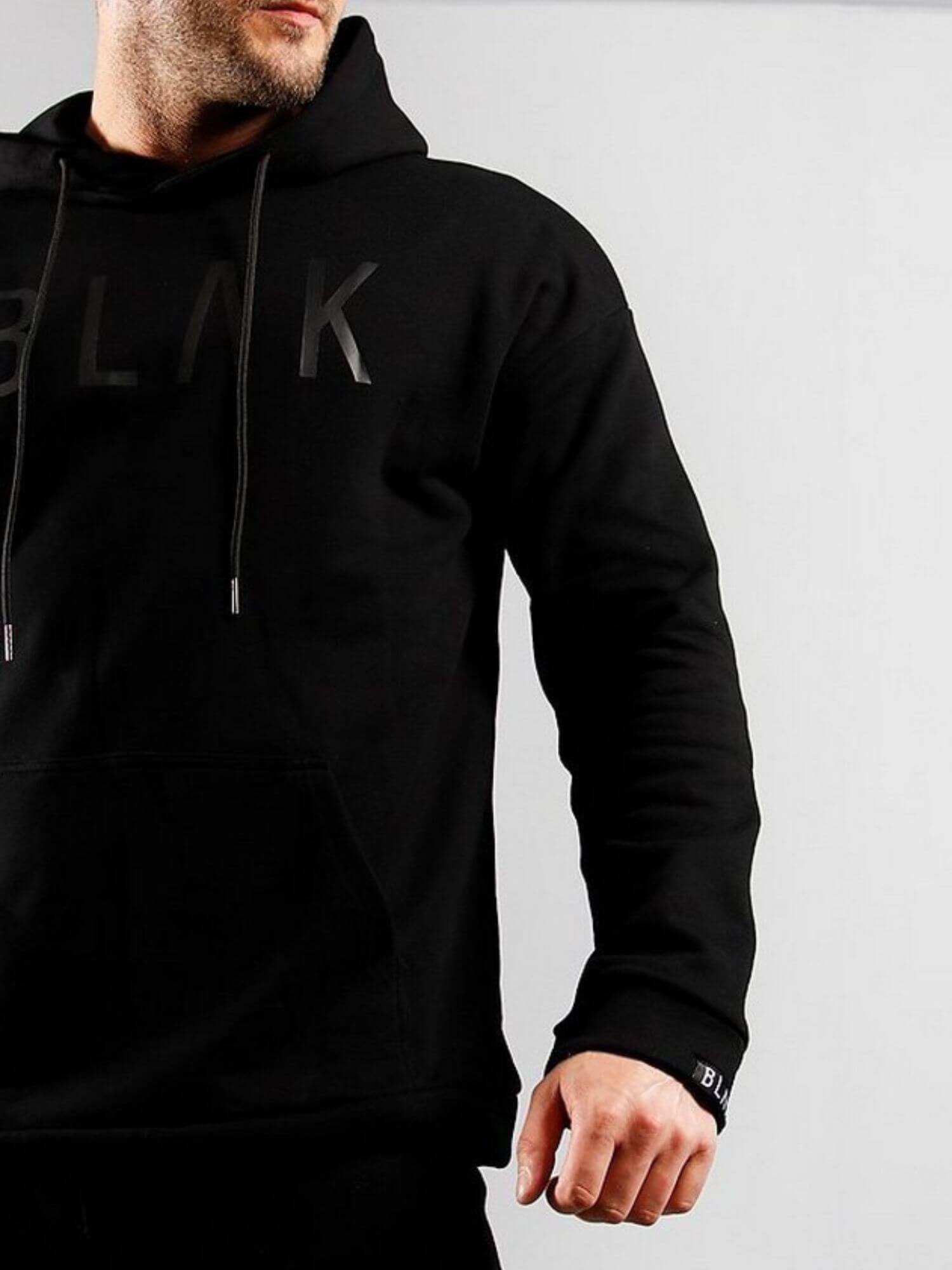 Person wearing a black hoodie with branding on a light gray background