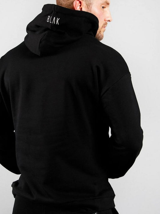 Person wearing a black hoodie with 'BLAK' branding on the back against a gray background