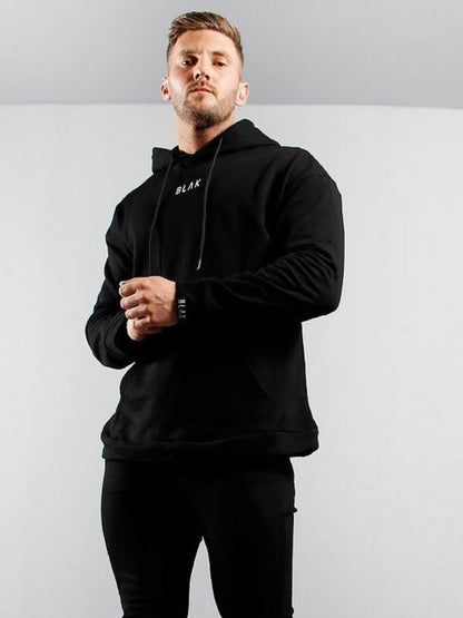 Man wearing a black hoodie with a brand logo on a gray background