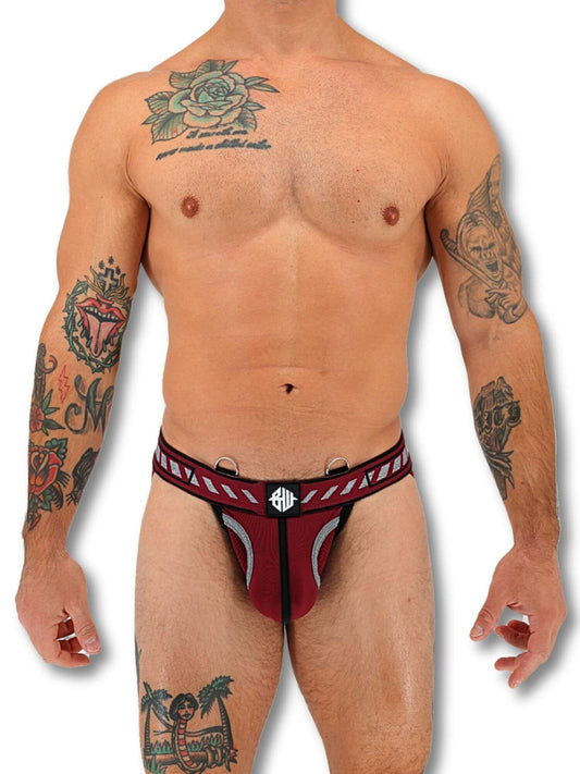 Man wearing a red and black jockstrap with a visible brand logo on a white background
