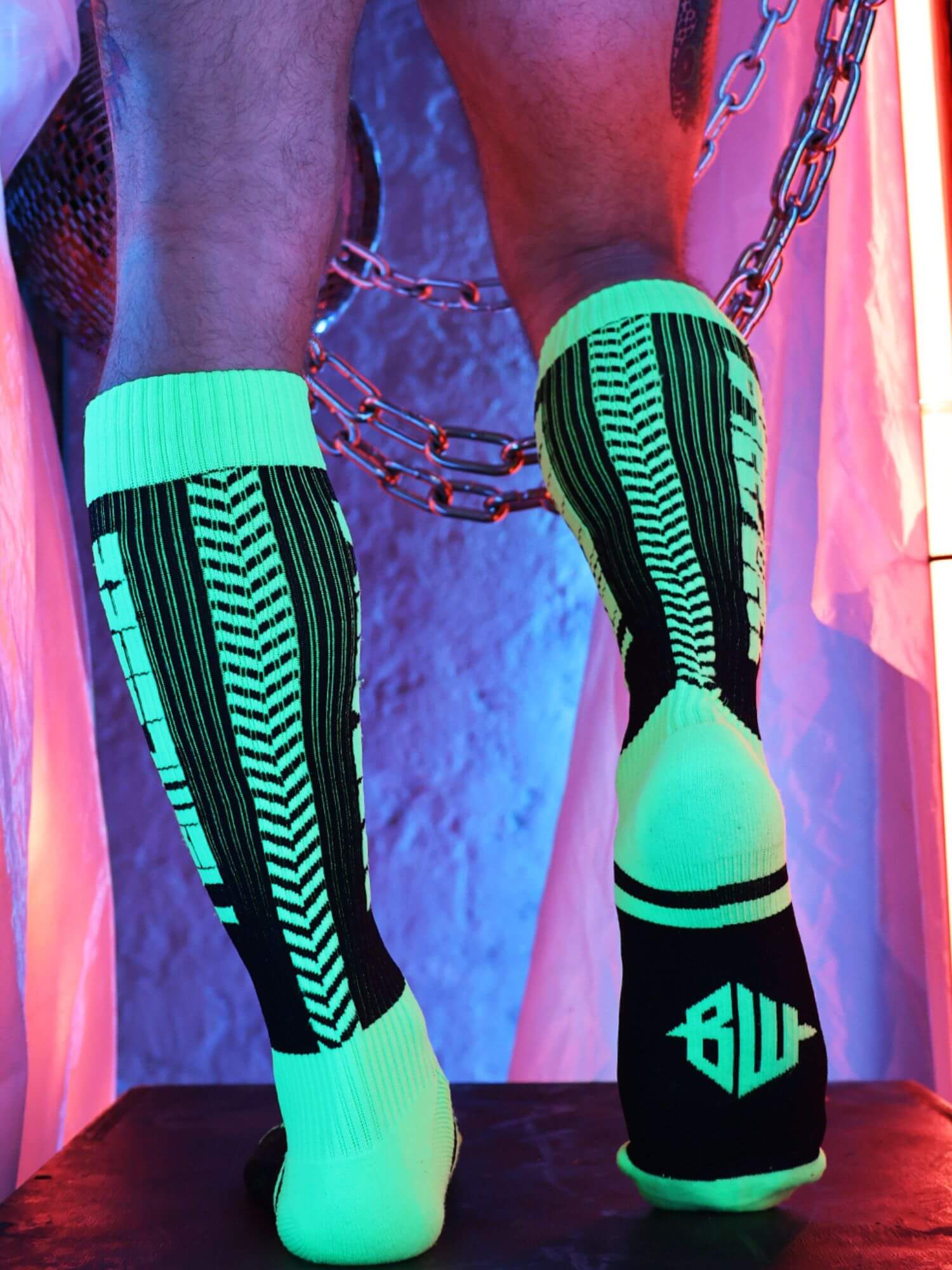 Glowing green and black socks with a brand logo on a reflective surface.