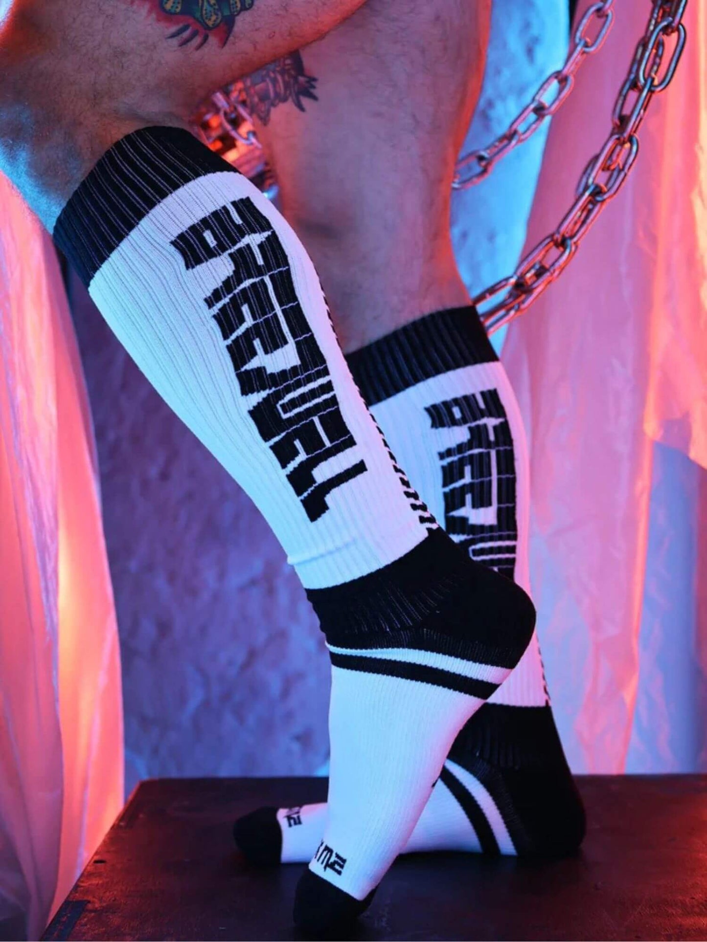 White knee-high socks with black text worn by a person, against a colorful background.