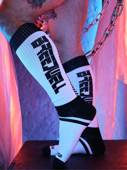 White knee-high socks with black text worn by a person, against a colorful background.