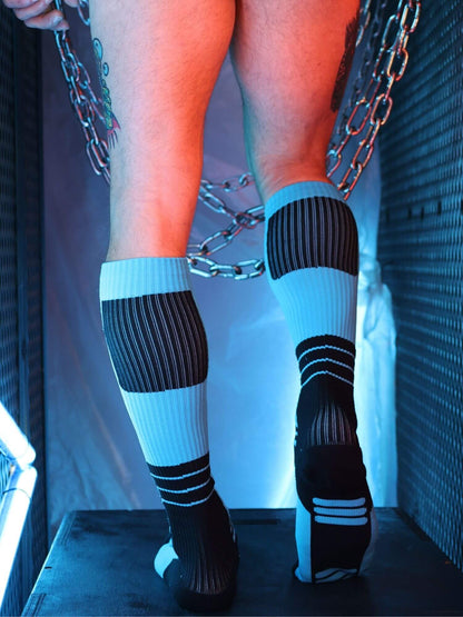 Person wearing black and aqua striped socks with a chain-link fence in the background
