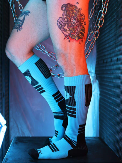Person wearing knee-high socks with black stripes, standing against a dark background.