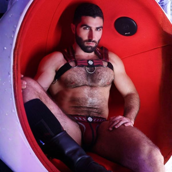Man sitting inside a red and white pod with a harness on.