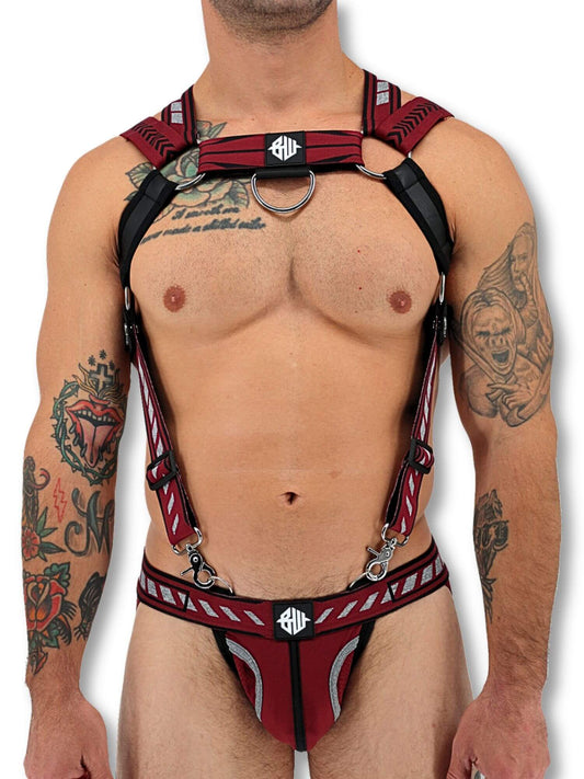 Man wearing a red and black harness with visible tattoos on a white background