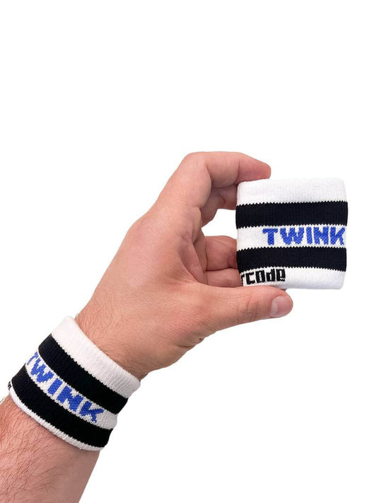 A hand holding two white wristbands with gay pride stripes