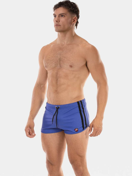 Man wearing blue swim shorts with black stripes on a white background