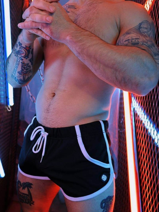 Man wearing black shorts with white drawstrings in a dimly lit room.