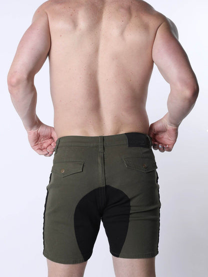 Rear view of a shirtless man wearing olive green riding shorts with a black rear panel and side detailing, against a plain light background.