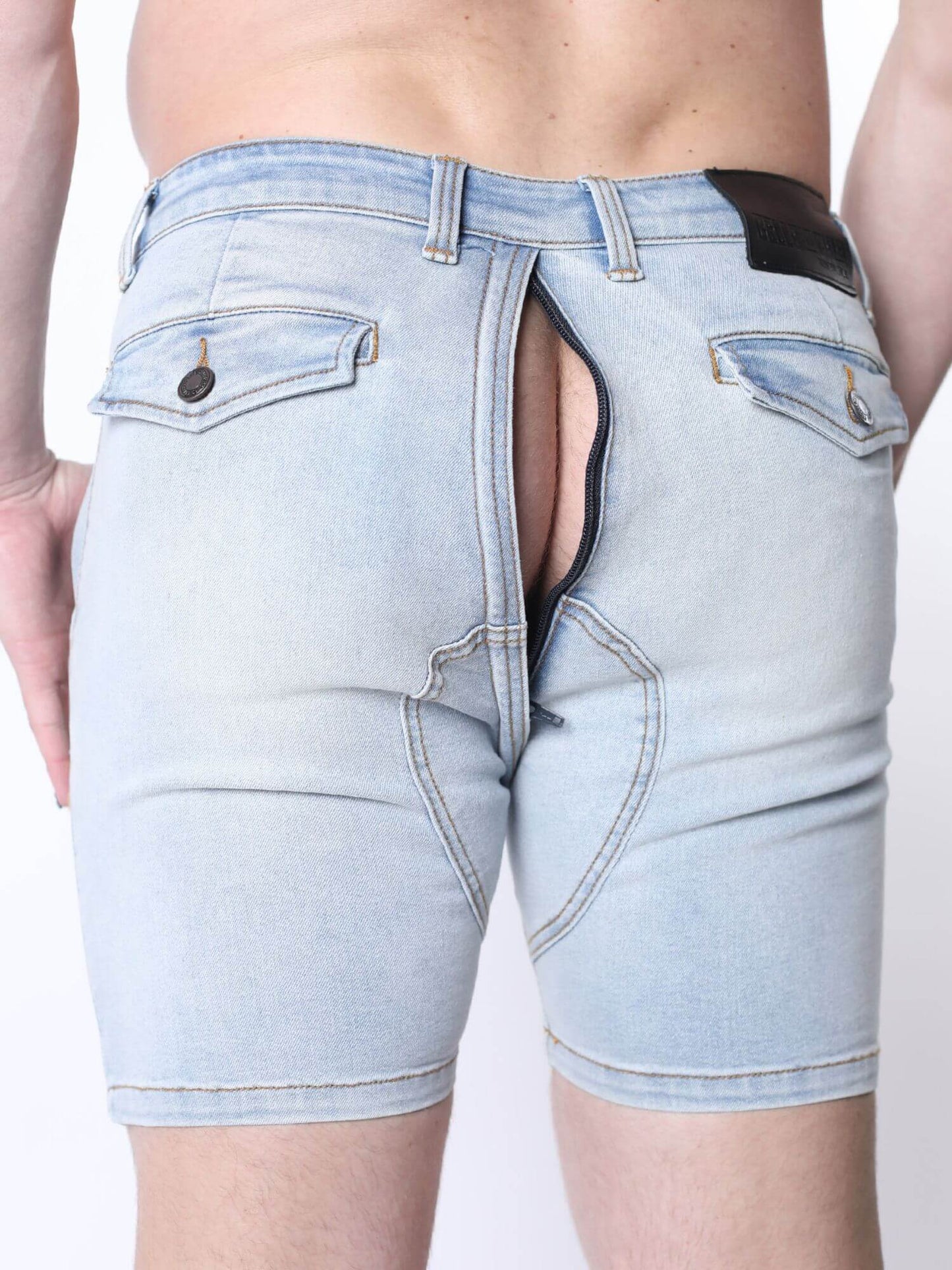 Light wash blue denim shorts with a unique open-back design showing a black interior lining, modeled from behind on a white background.