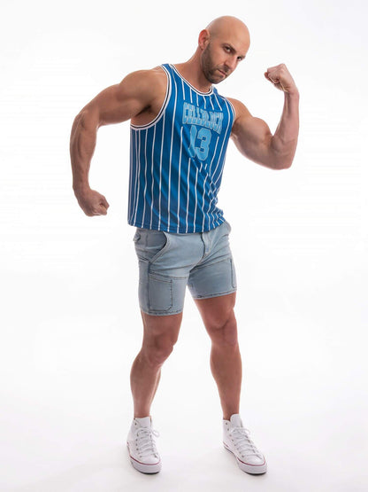 A muscular man posing in a blue and white vertically striped athletic tank top with a graphic on the chest, paired with light-wash denim shorts and white sneakers, against a plain white background.