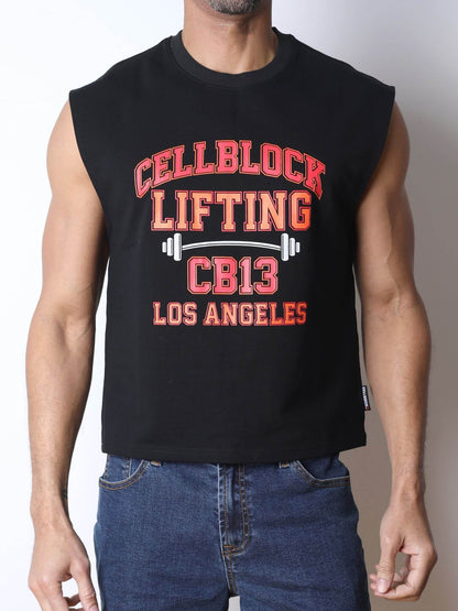 A man wearing a black sleeveless muscle tank top with a distressed red and white graphic that reads 'CELLBLOCK LIFTING CB13 LOS ANGELES' with a barbell design, paired with blue jeans against a plain light background.