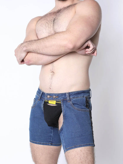 A shirtless man wearing blue denim shorts with a black pouch-like front pocket and a yellow label, posed against a plain light background.