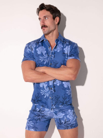 Man wearing a blue floral shirt and shorts set against a white background