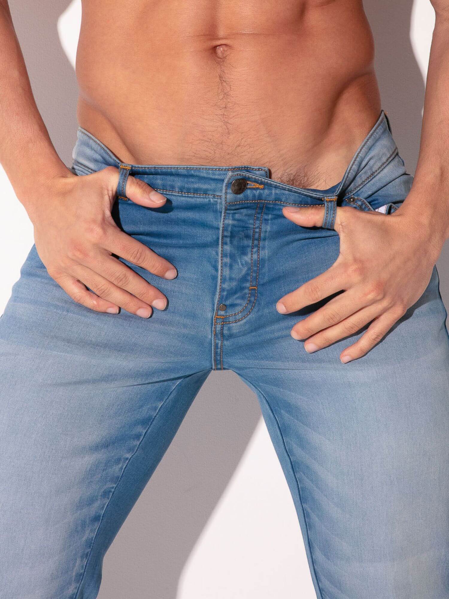 Person wearing light blue jeans with a neutral background