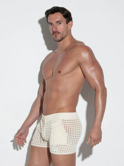 Man wearing white crochet shorts against a plain background