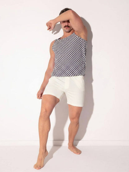 Person wearing a sleeveless patterned top and white shorts on a plain background