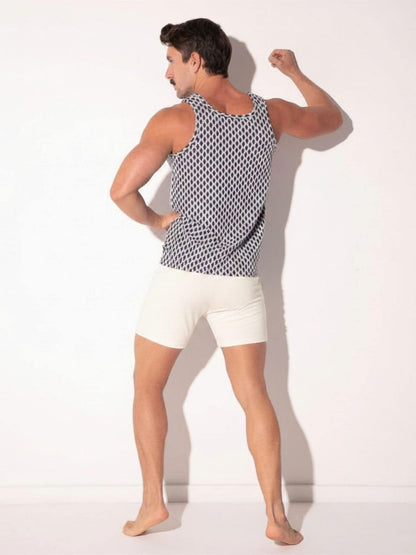 Man wearing a patterned tank top and white shorts on a plain background