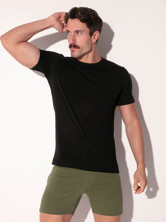Man wearing a black t-shirt and green shorts against a white background