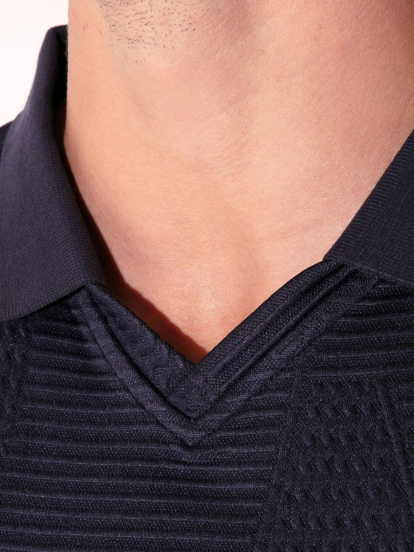 Close-up of a person wearing a dark blue textured sweater with a collar.