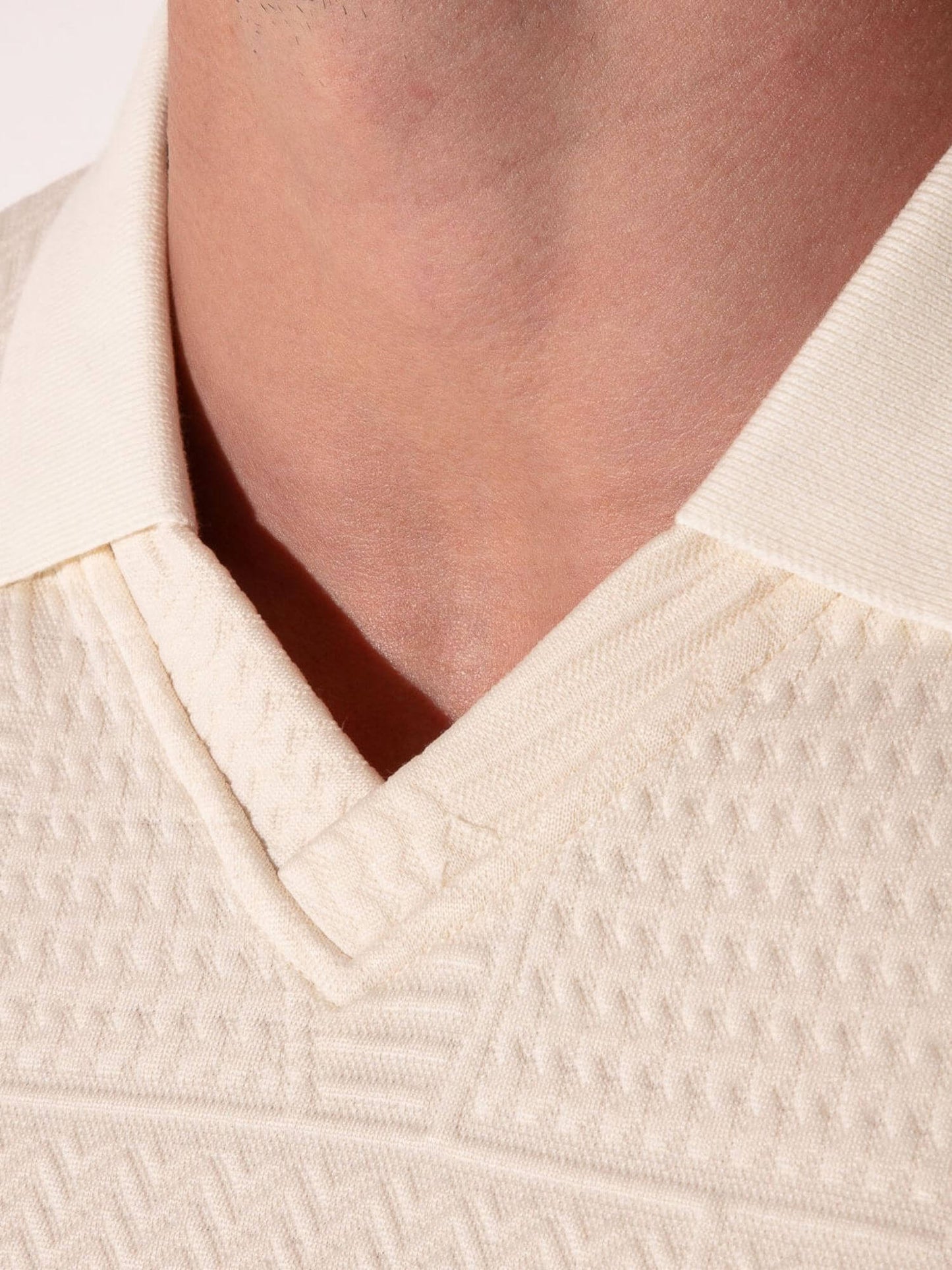 Close-up of a textured off-white garment with a V-neckline