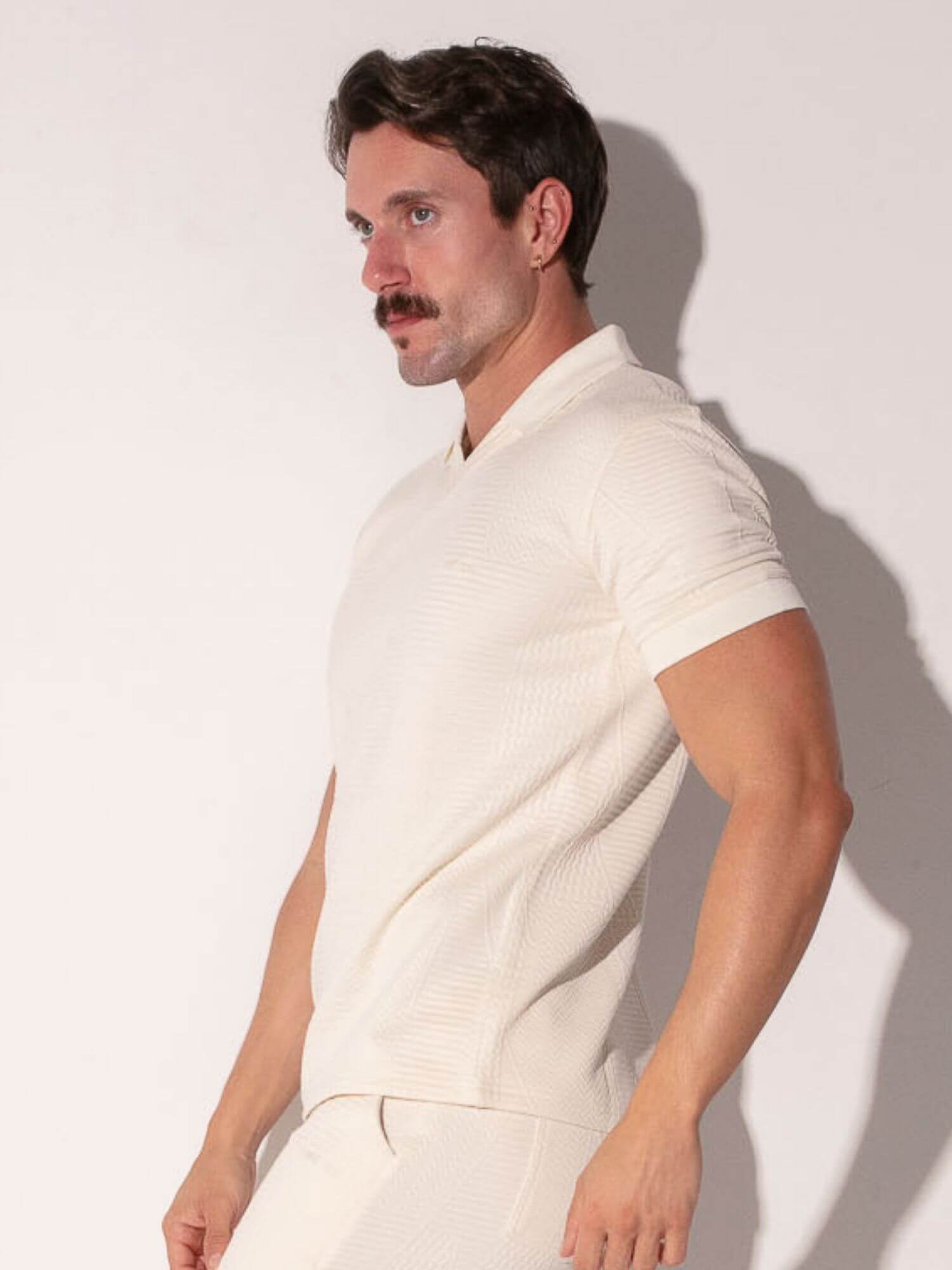 Man wearing a off-white outfit against a plain background