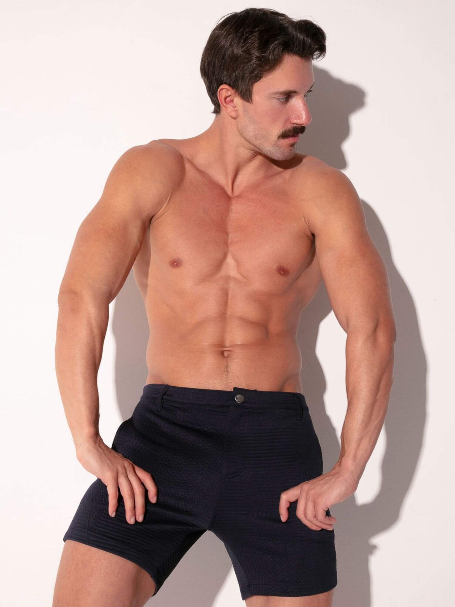 Man wearing navy pocket shorts against a white background