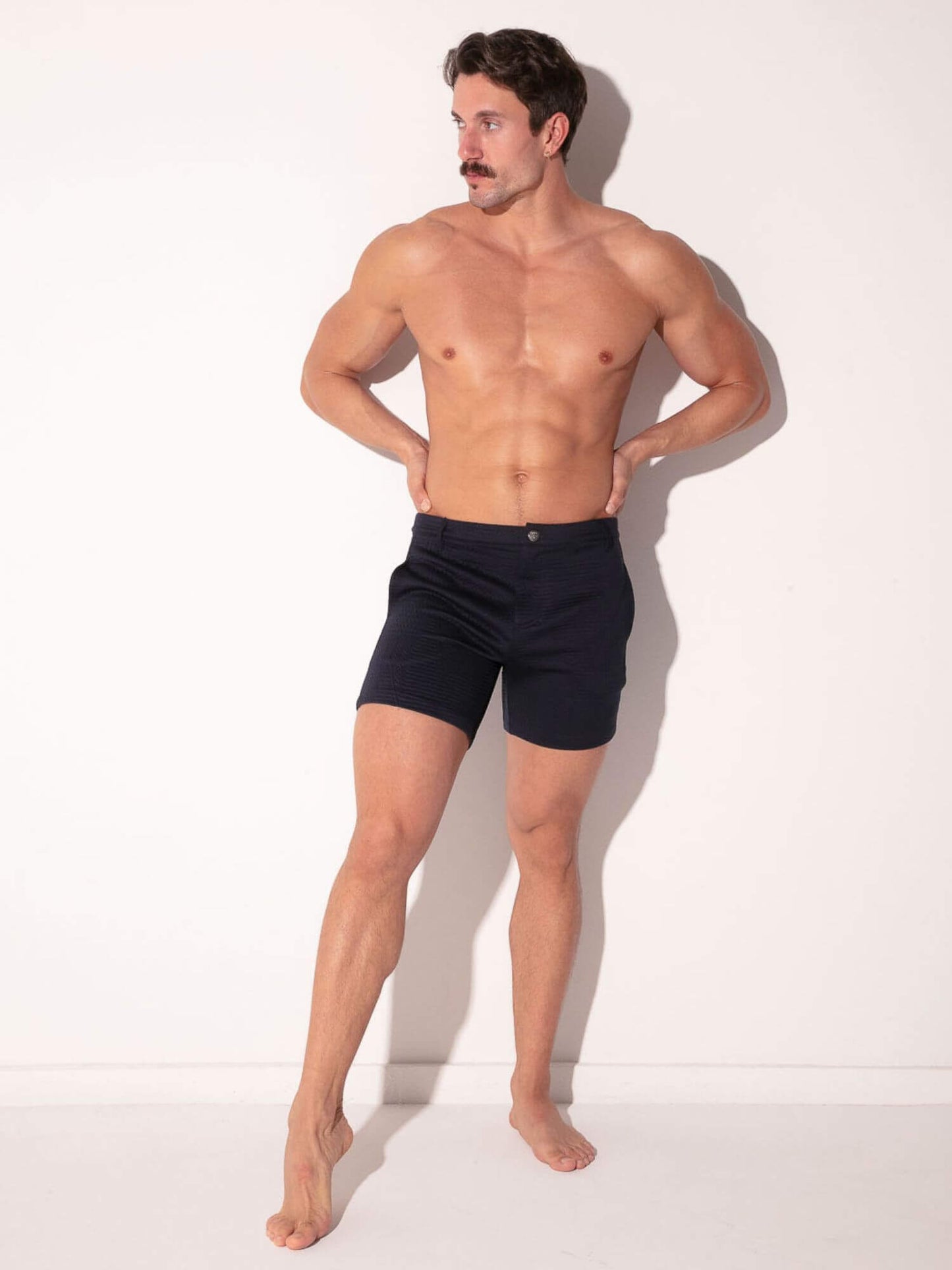 Man wearing navy shorts with subtle geometric pattern on a white background