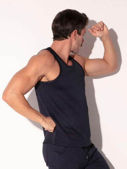 Man wearing a navy tank top and pants against a white background