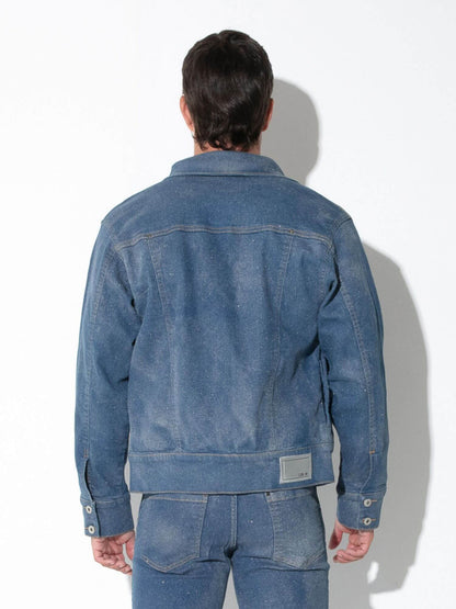 A man viewed from behind wearing a faded blue denim jacket and matching blue denim jeans against a plain white studio background.