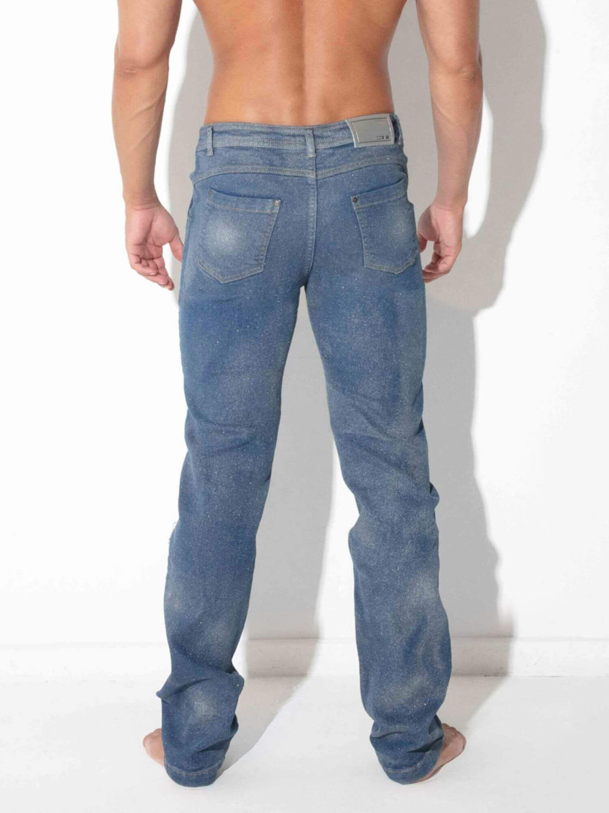 Rear view of a man wearing blue denim jeans against a white background.