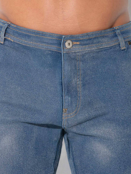 Close-up of a person wearing blue denim jeans, showing the waistband, button, front pocket, and thigh area against a plain light background.
