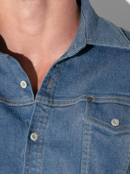 Close-up of a person wearing a blue denim button-up shirt, showing the collar, chest pocket, and front buttons.