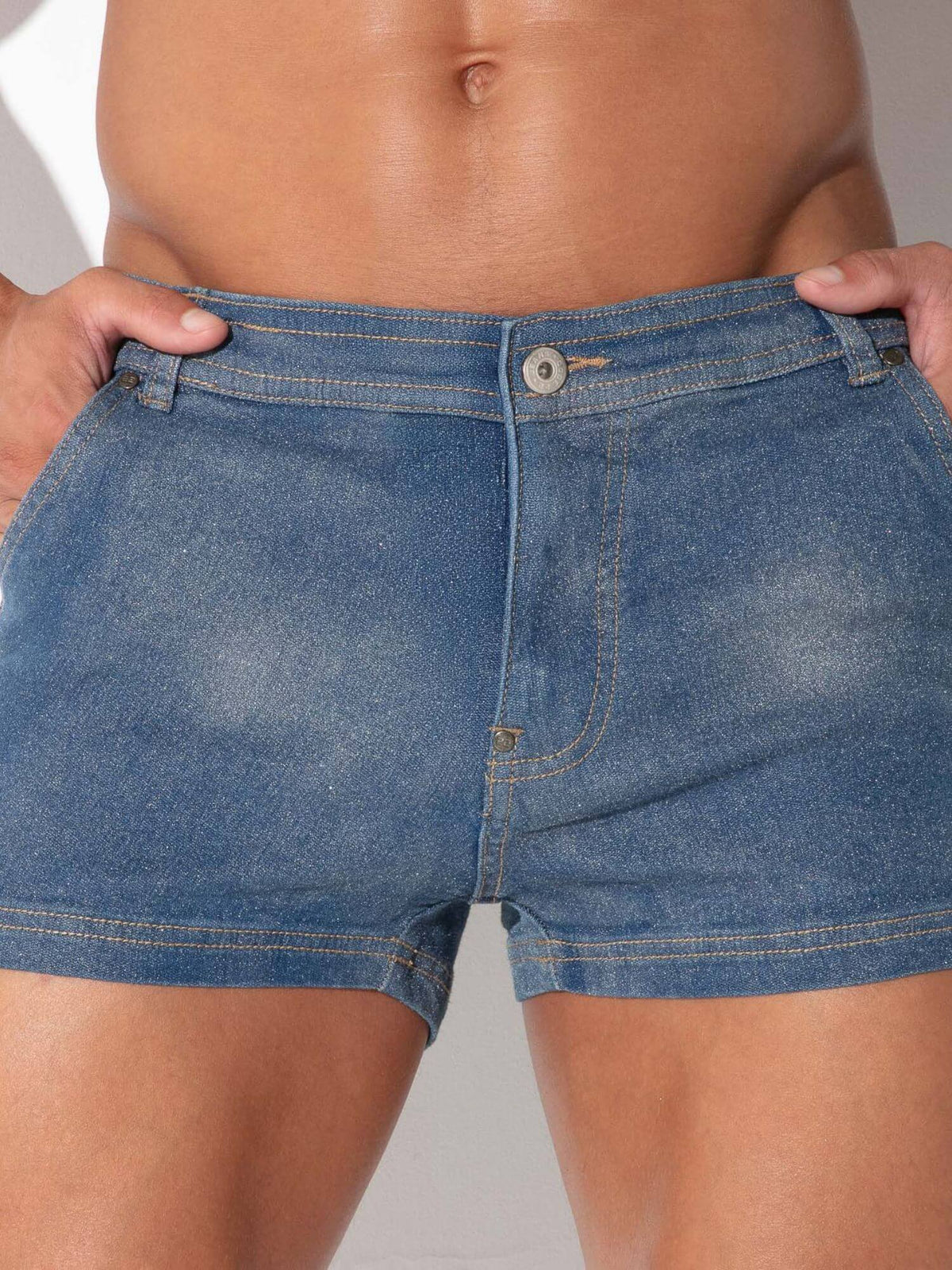 Close-up of a person wearing blue denim shorts, with hands pulling the waistband slightly outward to show the fit.