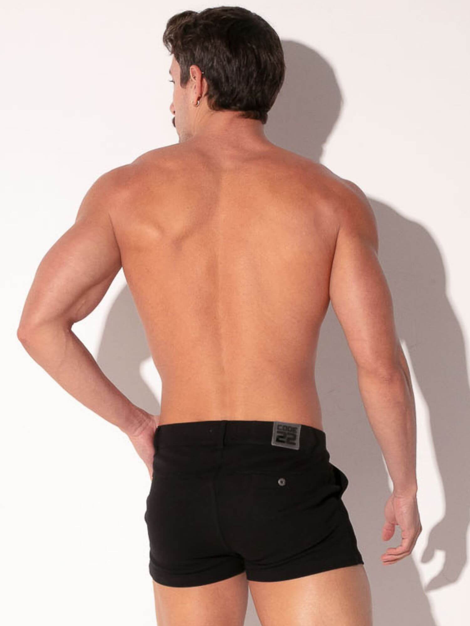 Man wearing black boxer briefs against a plain background